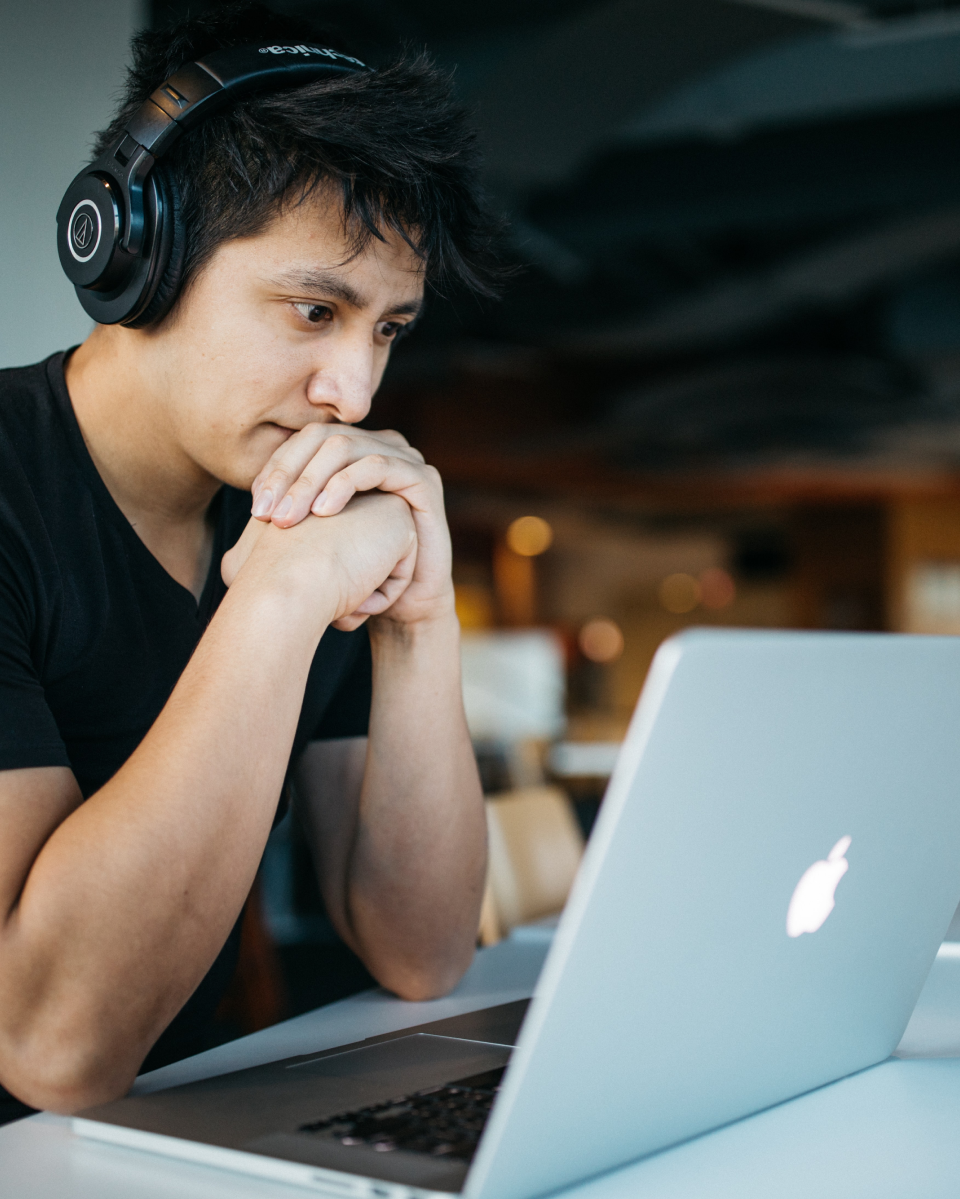 Student wearing headphones, focused on coding at a laptop, representing Sigma School's job-ready coding bootcamp.