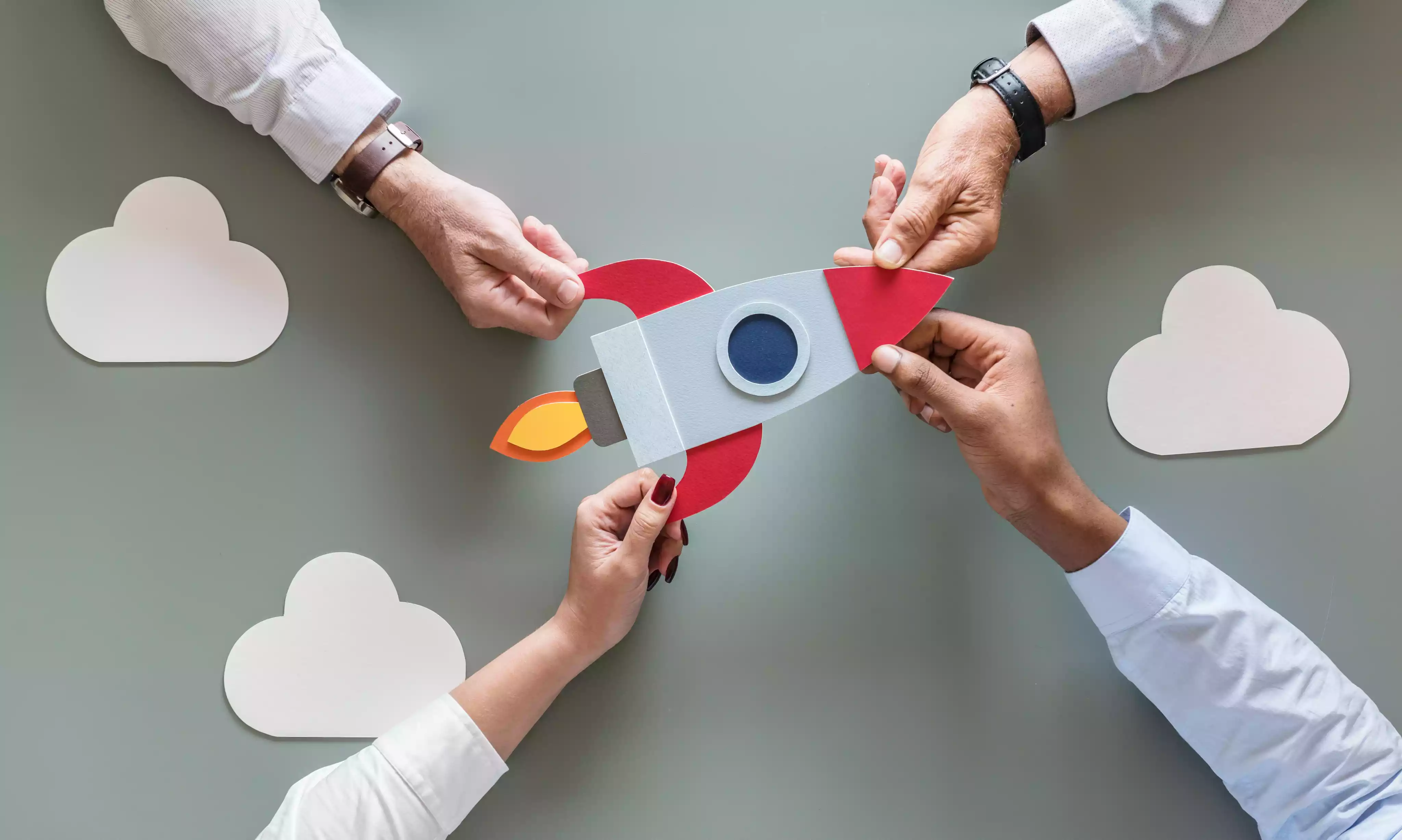 4 people holding a paper rocket