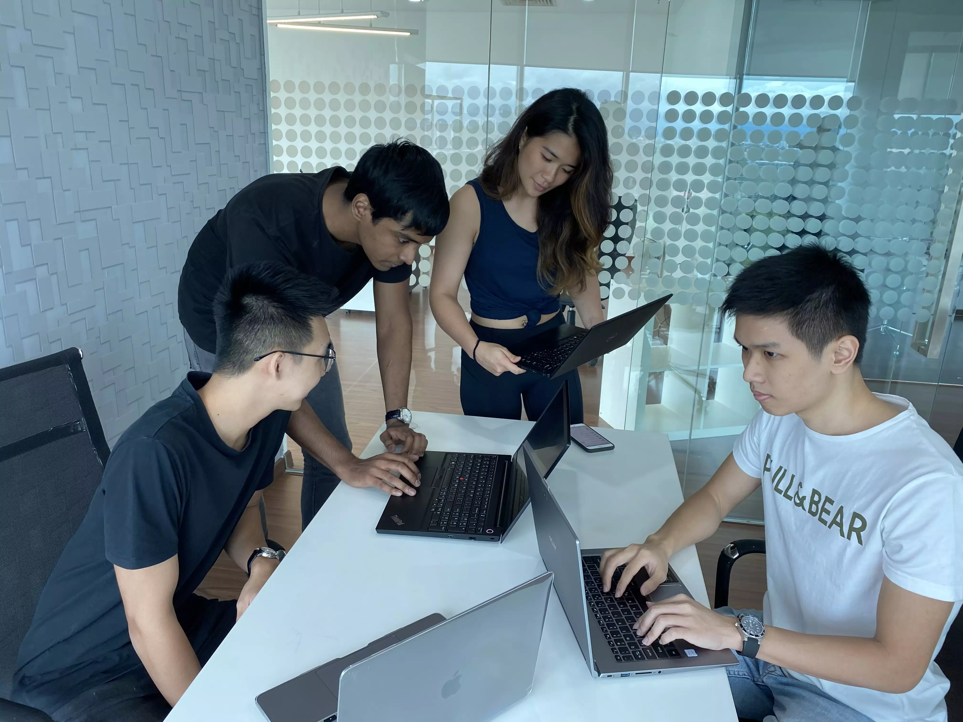 Group of students collaborating with a mentor on laptops showcasing Sigma School's supportive learning environment with mentors, career coaches, and real-world project reviews guiding students through the full stack coding program