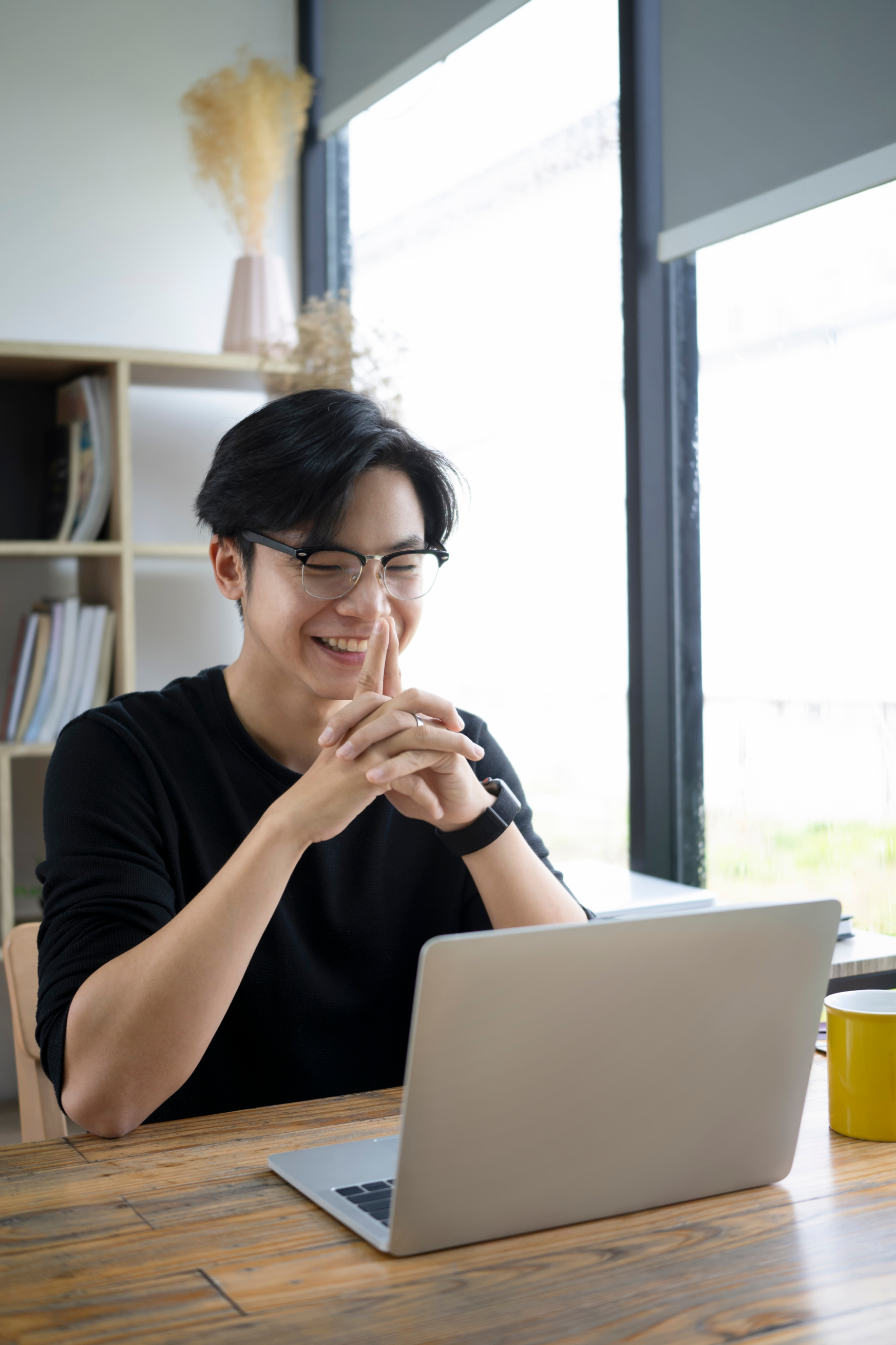 Student smiling while working on a laptop, symbolizing the confidence Sigma School builds in graduates by helping them polish their portfolios and prepared them for tech job interviews.